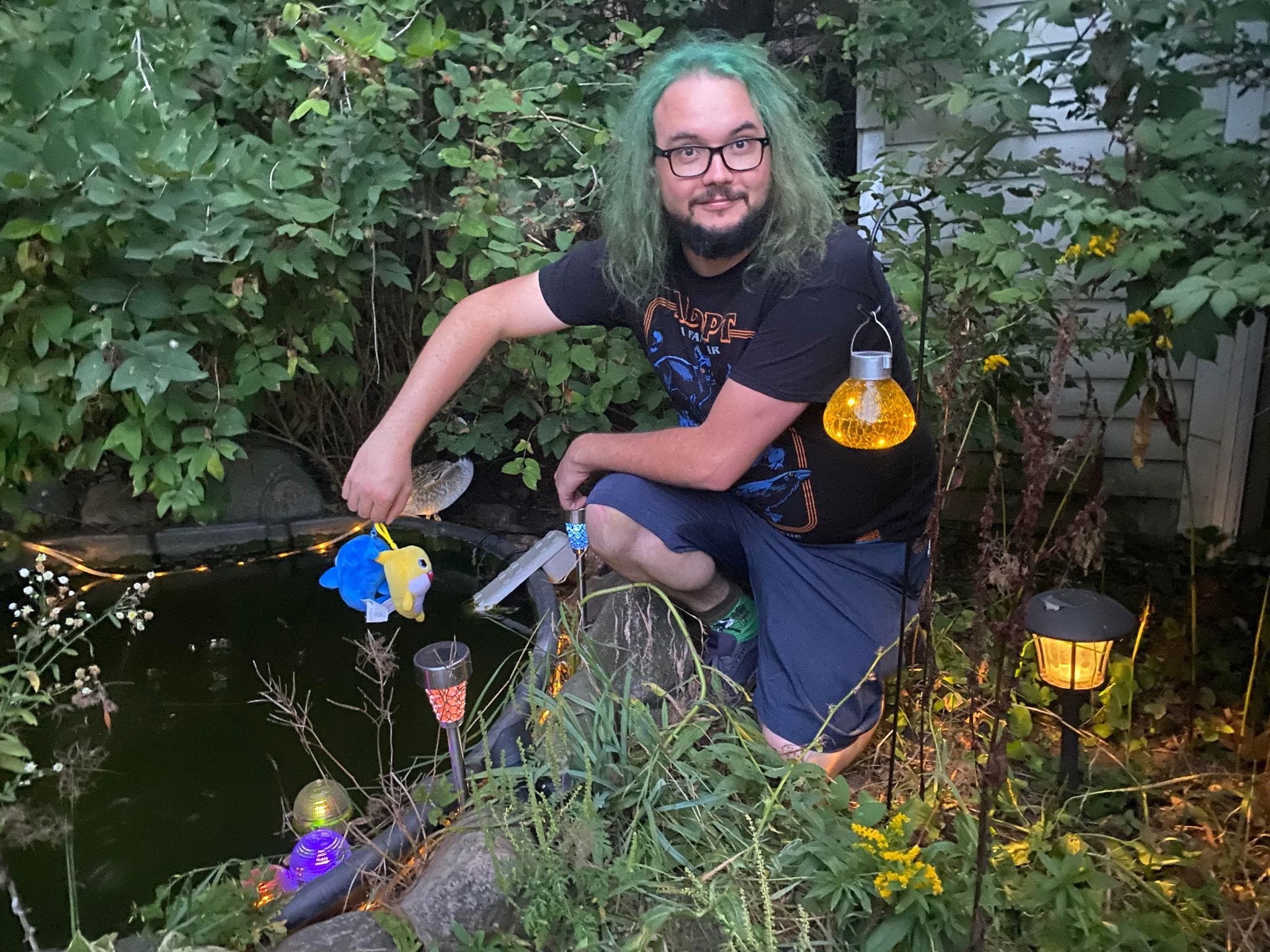 A man with green hair shows off his fish toys as though they were an impressive catch, Photo 2